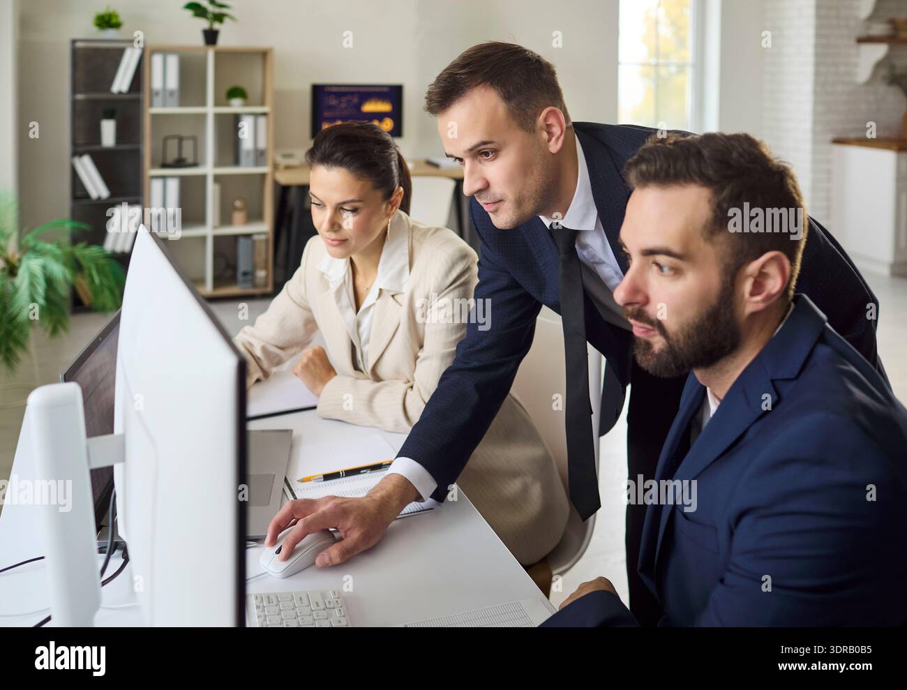 Business team analyzing data on computer in office, planning strategy together Stock Photo