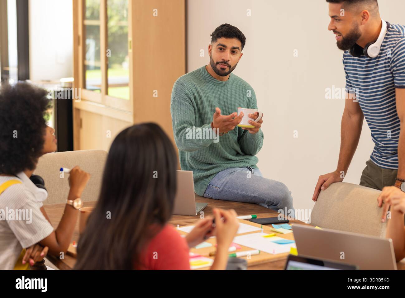 Discussing ideas, group of young friends collaborating with laptops and notes, start up business Stock Photo