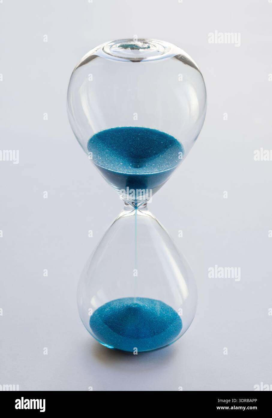 Hourglass containing blue sand isolated on white background Stock Photo