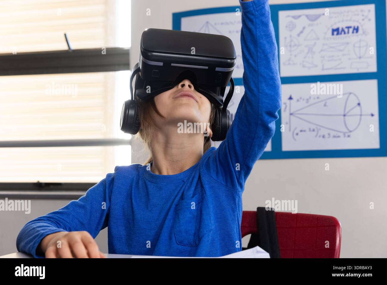 In school, boy using VR headset for interactive learning in classroom Stock Photo