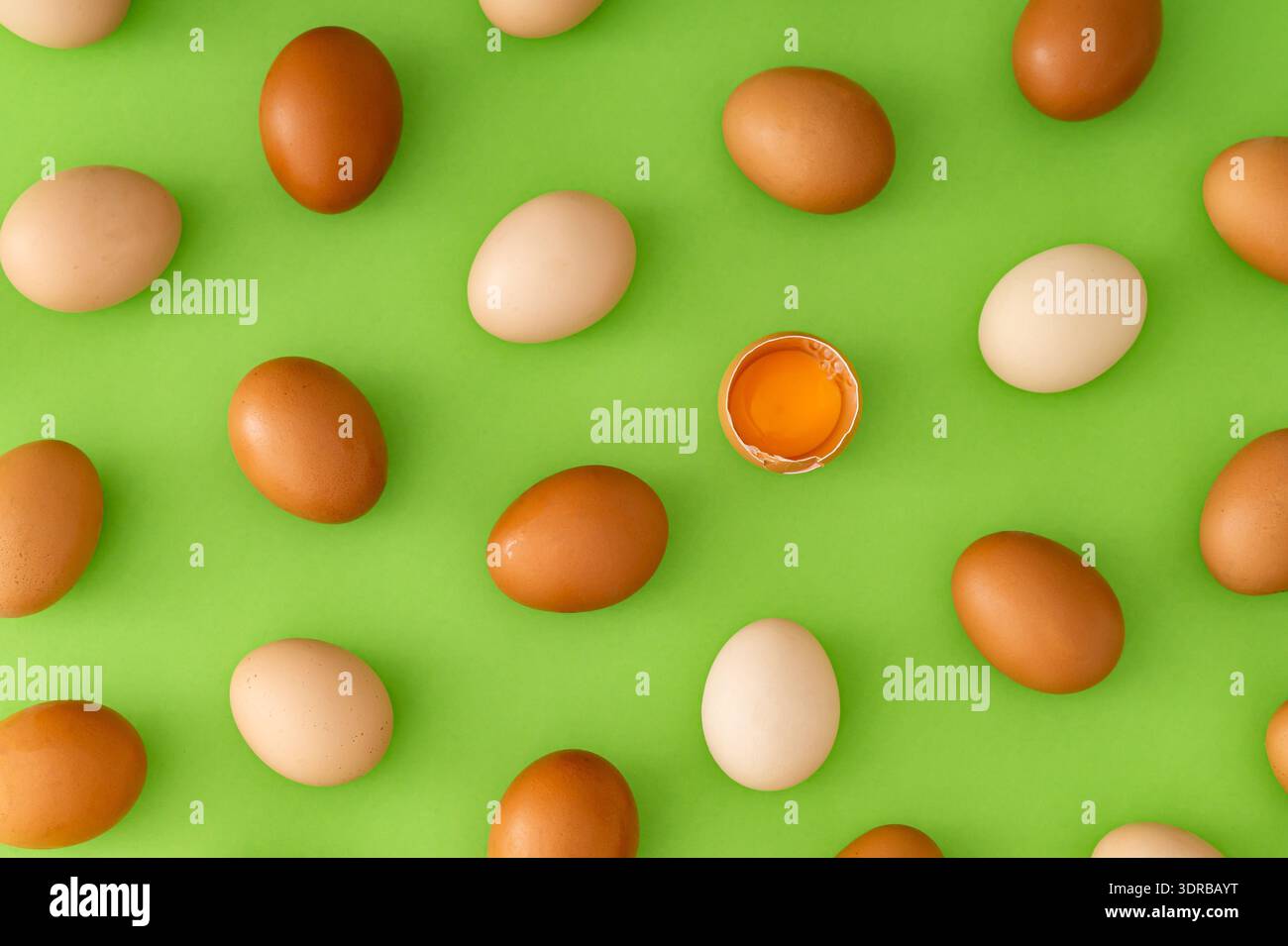 Food pattern made of natural fresh brown and white eggs with cracked egg and yolk on light green background. Creative food concept. Flat lay style. Stock Photo