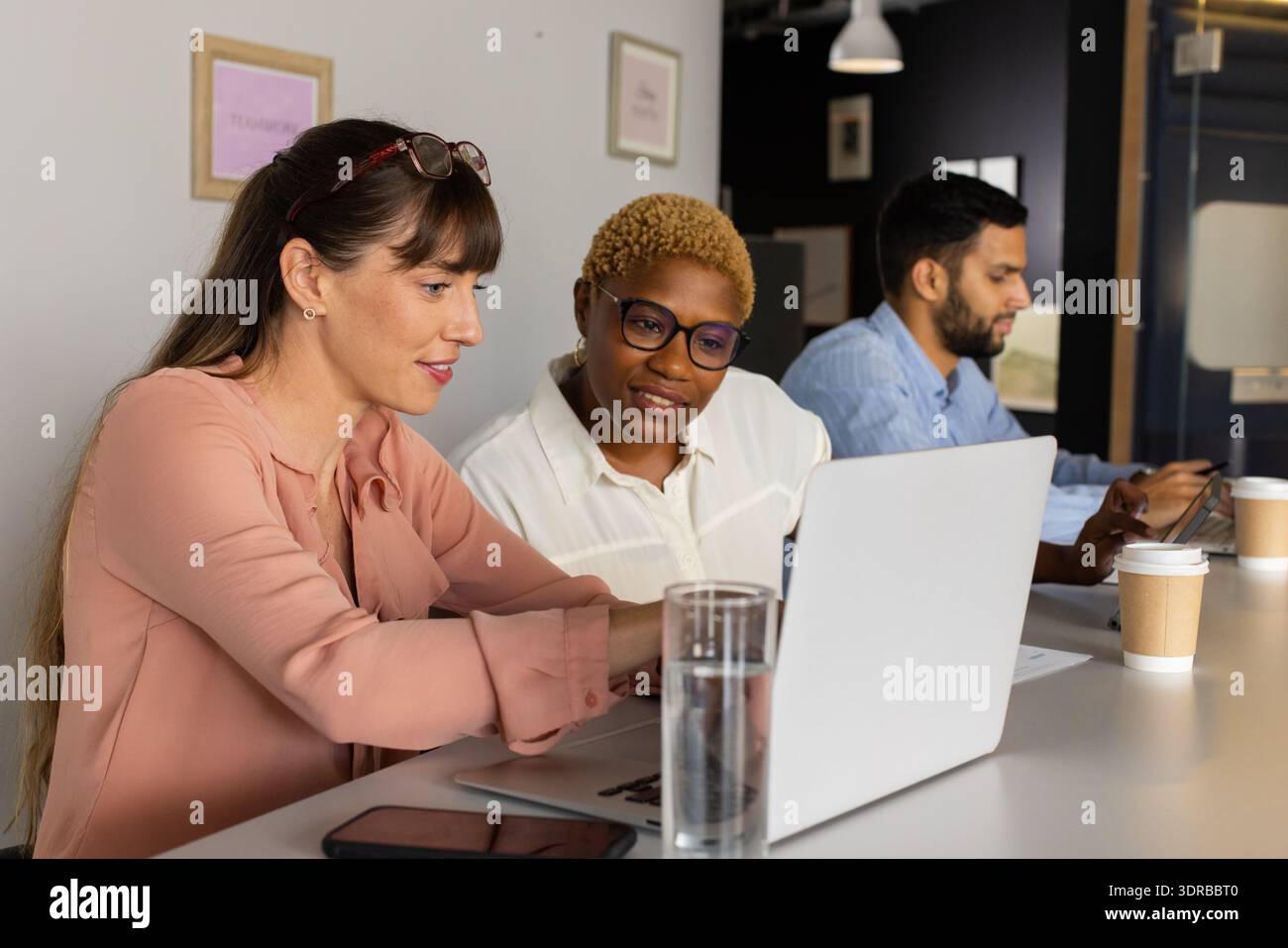 Collaborating on project, diverse team using laptop and smartphone in office Stock Photo