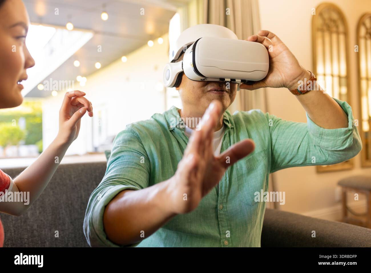 Using VR headset, father exploring virtual reality while daughter guiding him Stock Photo