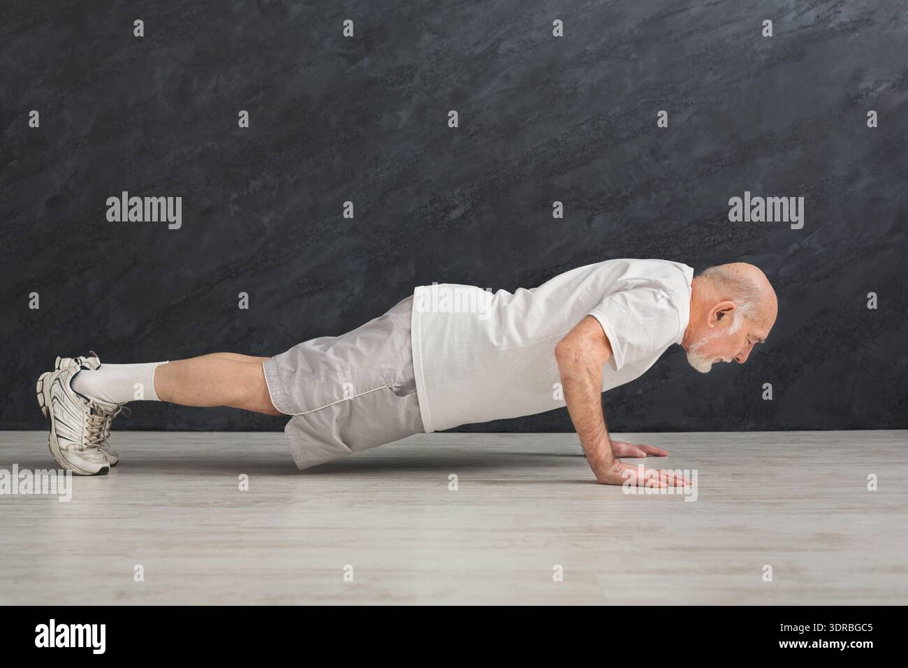 Senior Man Doing Push-Ups in Home Workout Setting During the Day Stock Photo