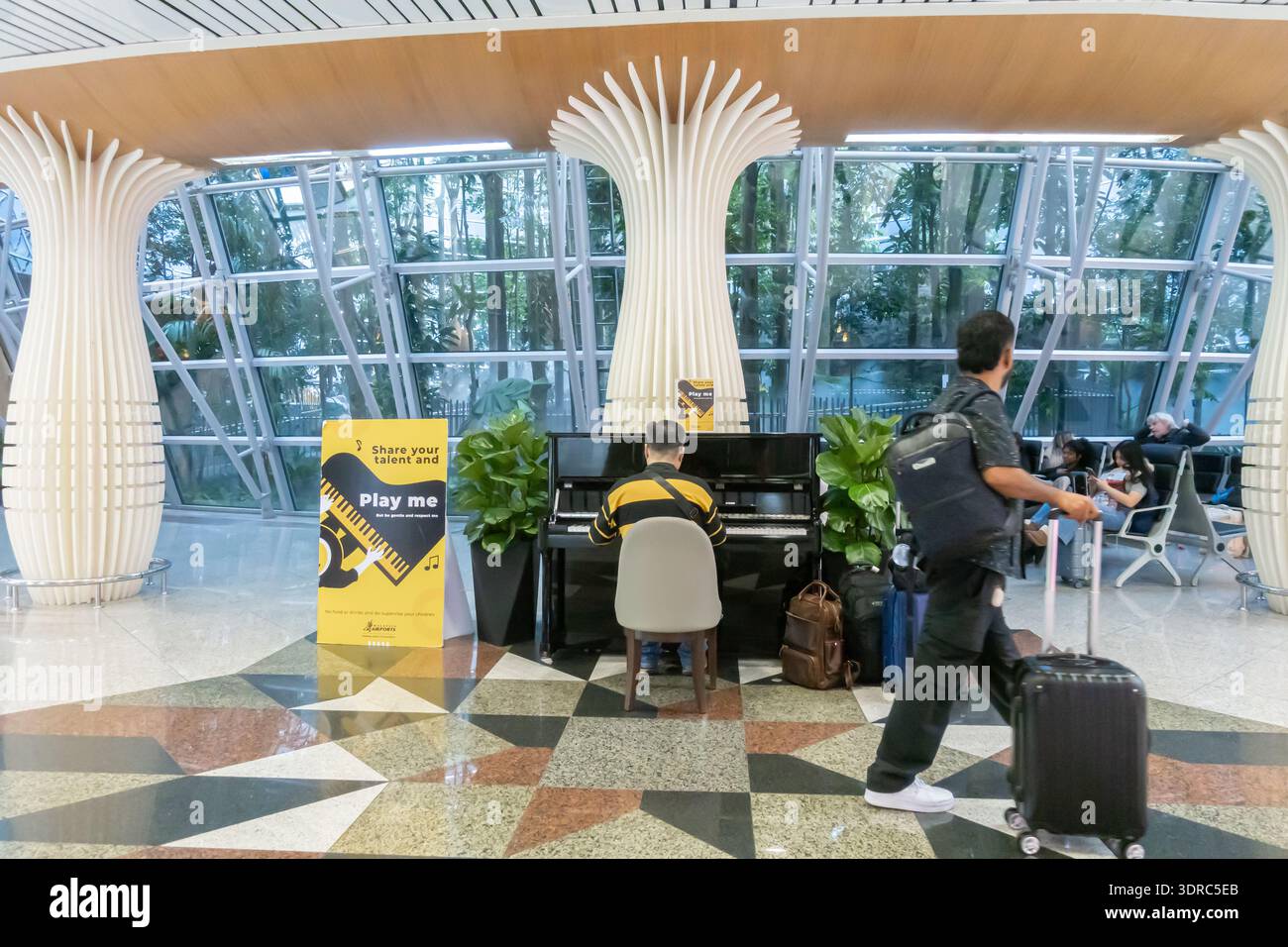 public piano performance in Kuala Lumpur airport, a traveler or visitor playing piano, "Share your talent and Play me" initiative, Stock Photo