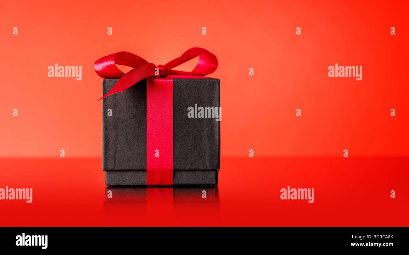 A black gift box adorned with a vibrant red bow Stock Photo