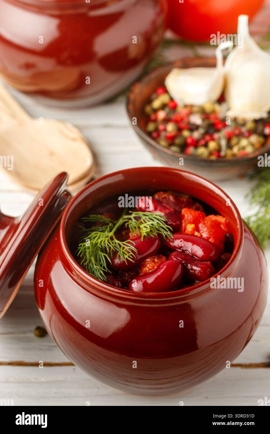 Stewed red beans with tomatoes and garlic in a ceramic pot. Vegetarian dish Stock Photo