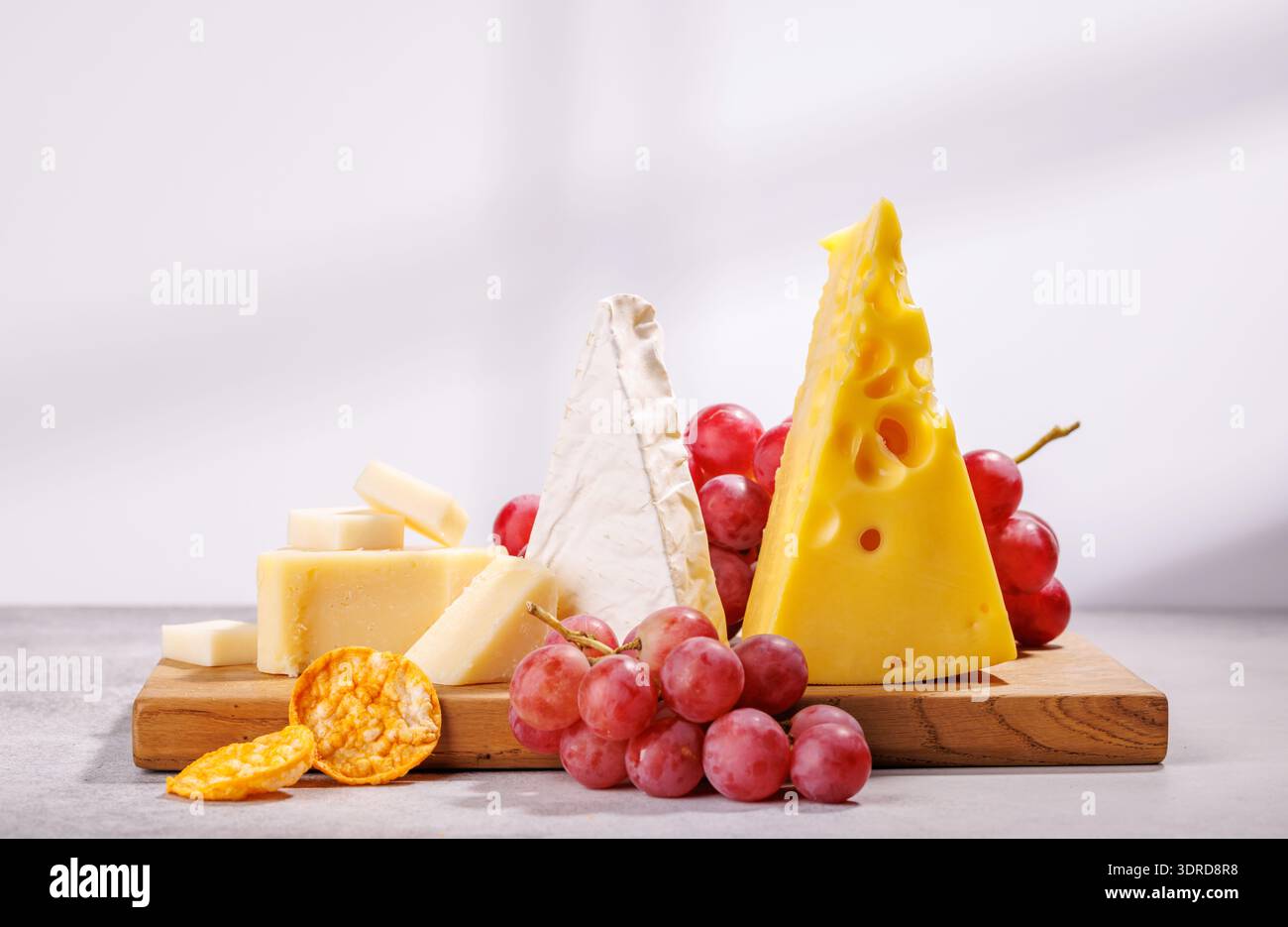 A delectable arrangement of various cheeses, fresh grapes Stock Photo
