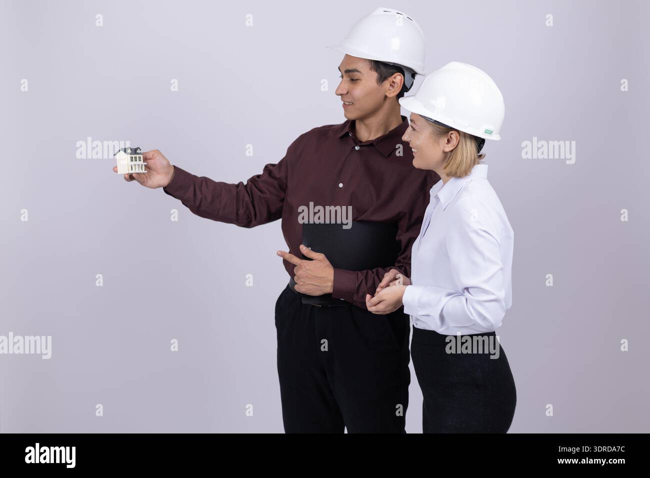 Engineer showing something on smartphone to female colleague Stock Photo