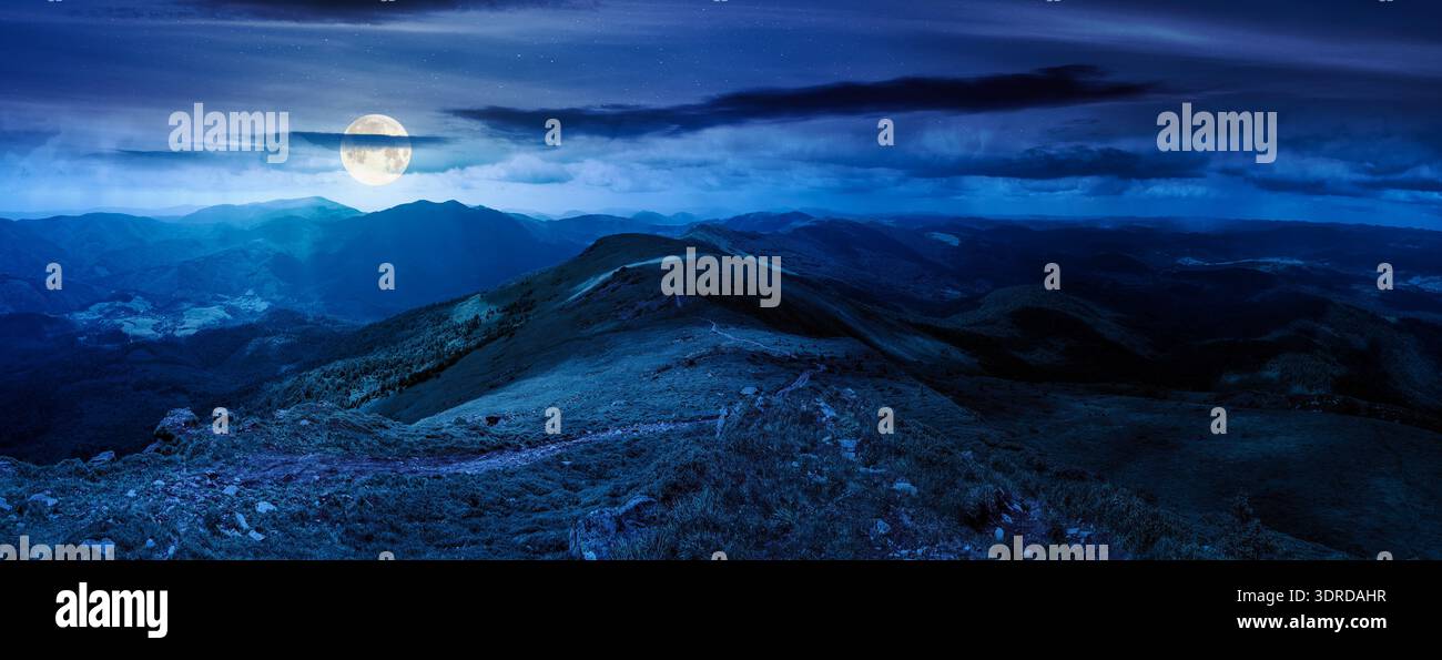 beautiful landscape of mountainous area on a summer night. panoramic view of great ridge in dappled full moon light. alpine scenery with path through Stock Photo