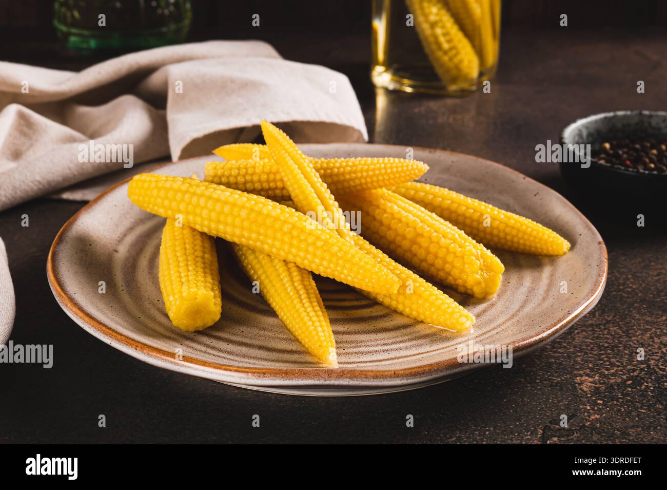 Canned mini corn cobs on a plate on a table Stock Photo