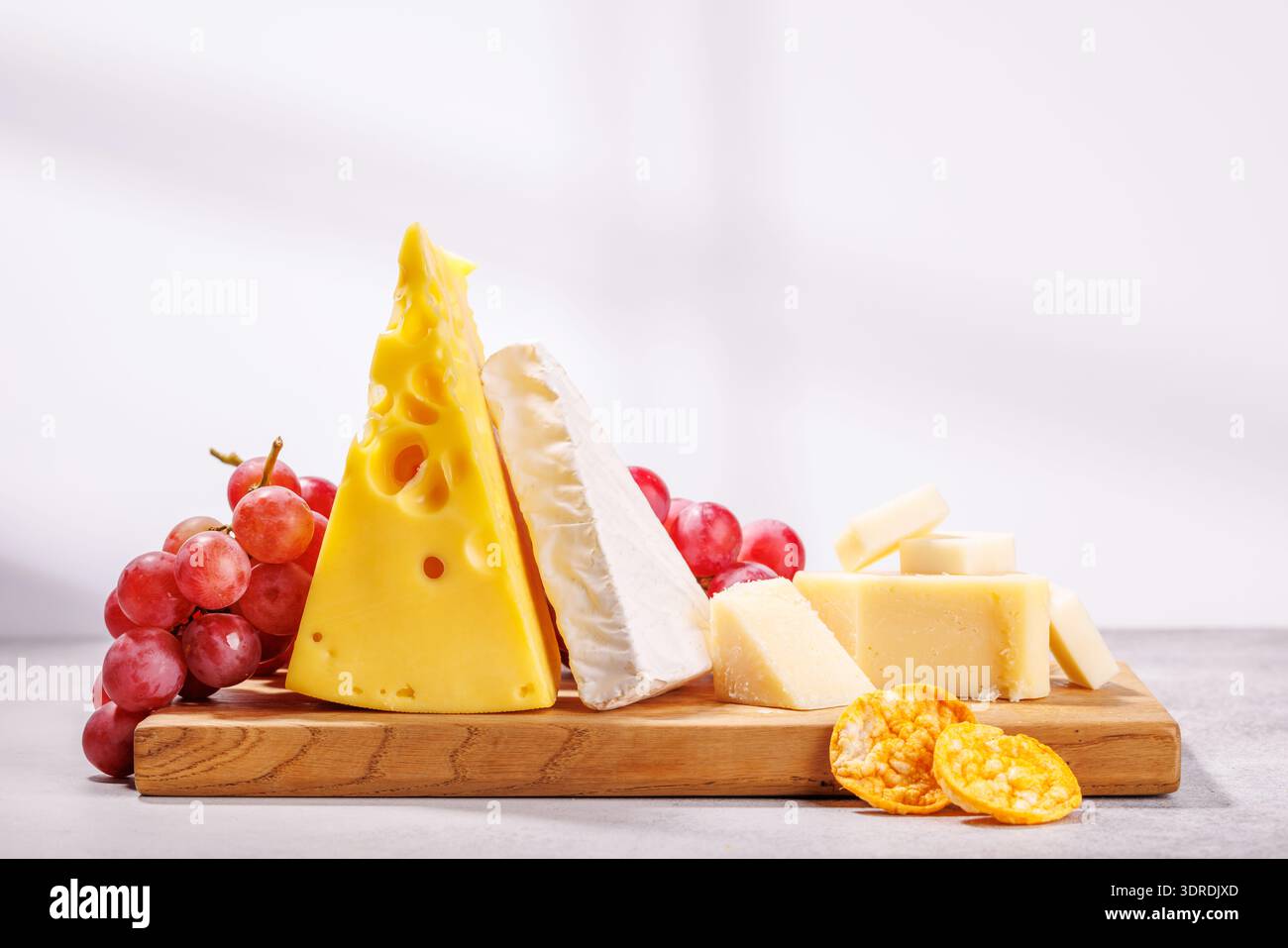 A delectable arrangement of various cheeses, fresh grapes Stock Photo