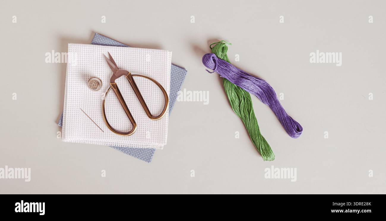 Canvas, threads and cross stitch tools on gray background top view web banner Stock Photo