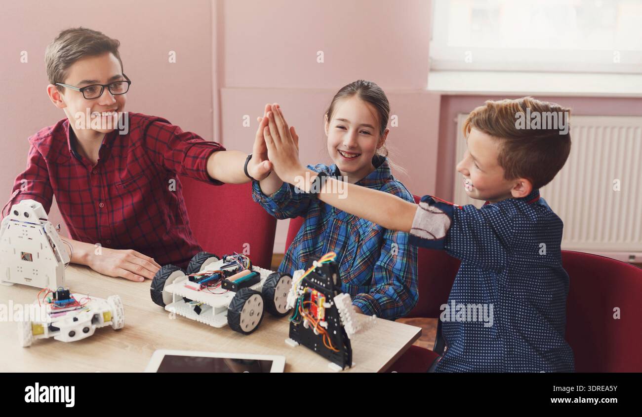 Kids Enjoy Teamwork While Building and Programming Robots in a Classroom Setting Stock Photo