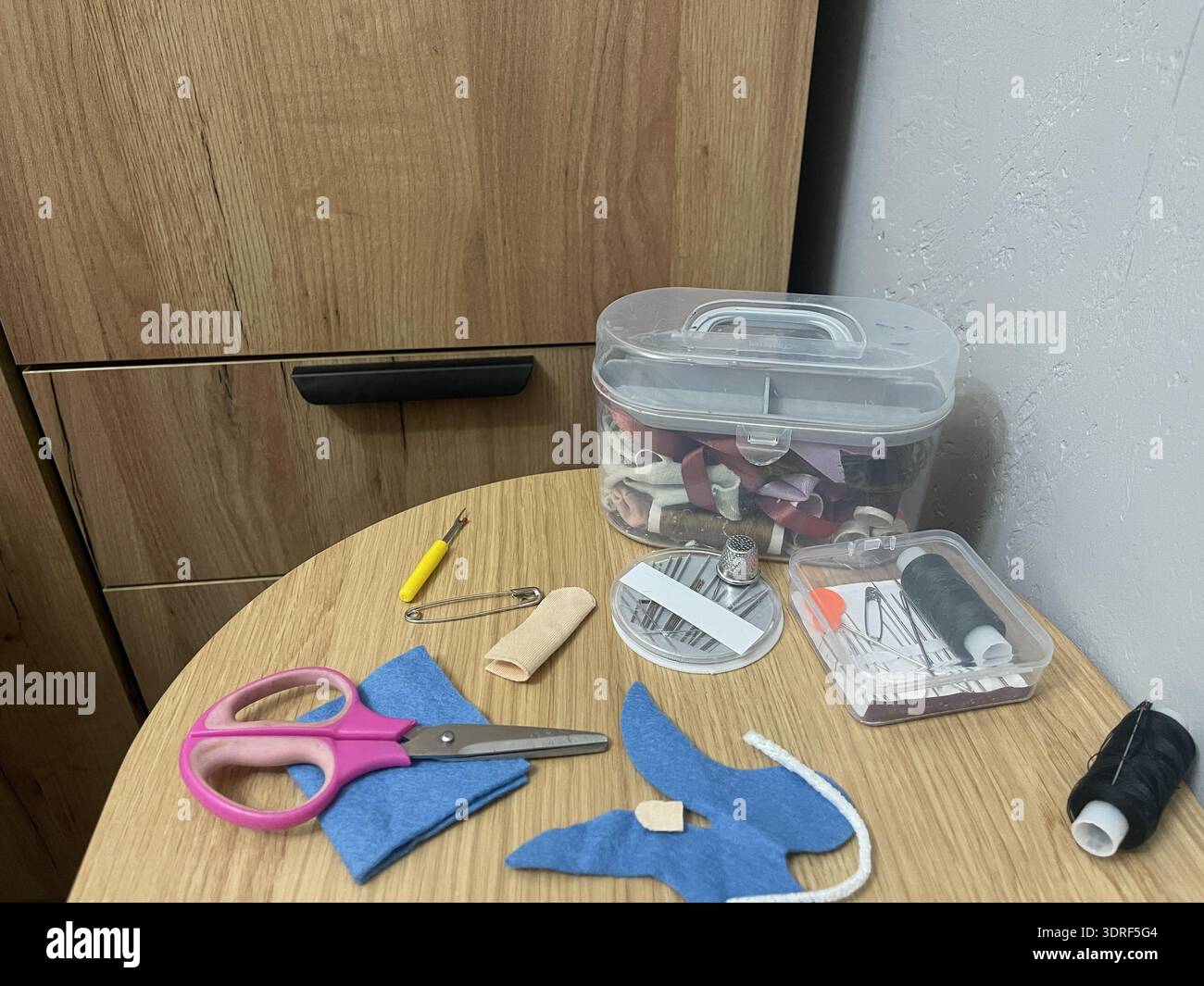 A tailor's sewing kit on a table. Needles, thread, and fabric for sewing. Stock Photo