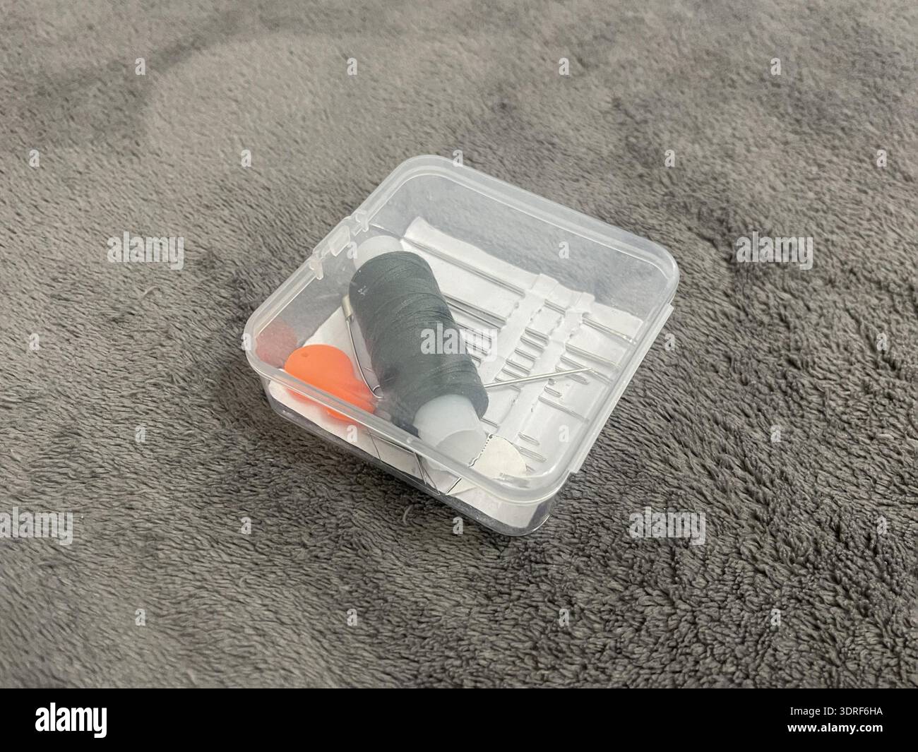 A tailor's sewing kit on a table. Needles, thread, and fabric for sewing. Stock Photo