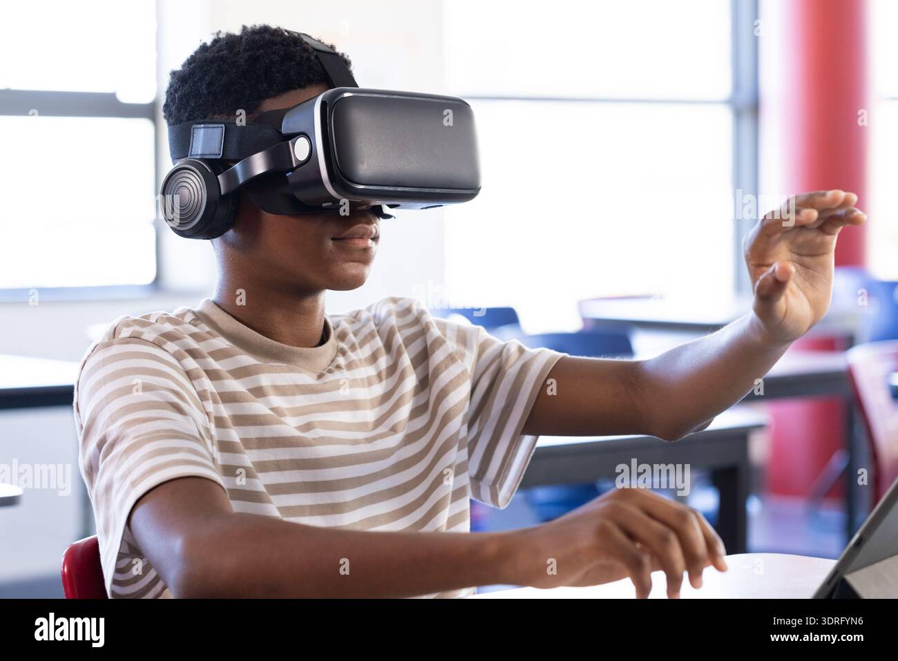 Using VR headset, student exploring virtual reality in school classroom. Technology, education, learning, innovation, digital Stock Photo