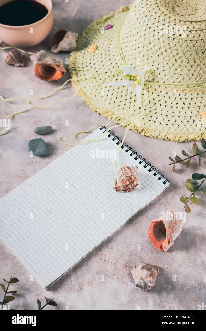Notebook, beach hat, shells and stones on the table vertical view Stock Photo