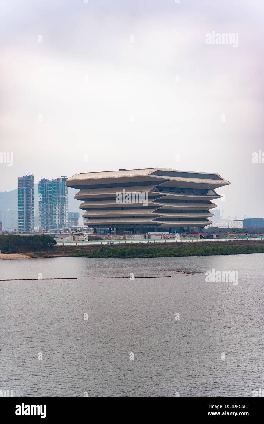 Modern layered building by river with city skyline in background ...