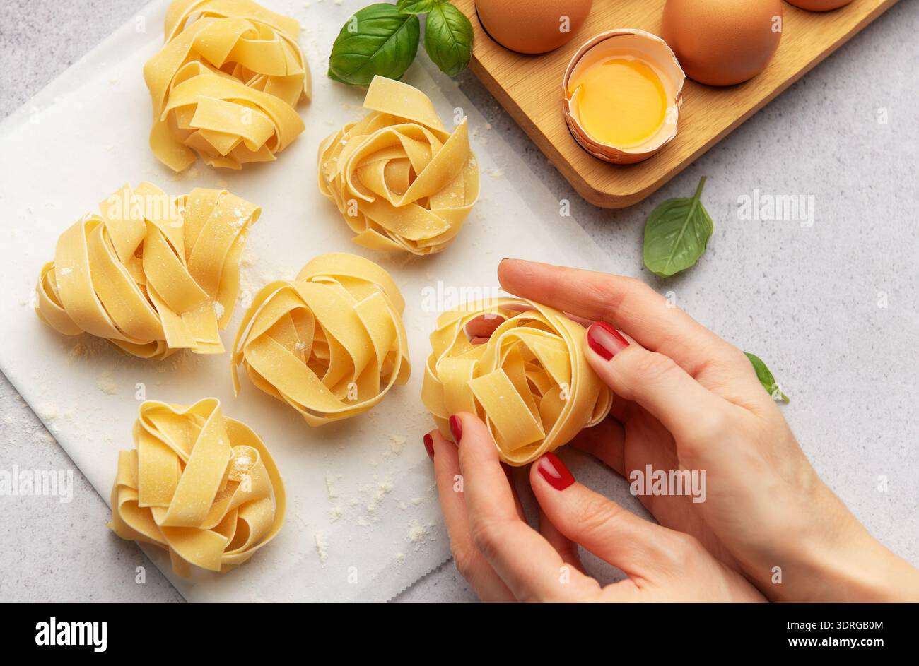 Chef preparing homemade tagliatelle pasta with eggs and basil Stock Photo