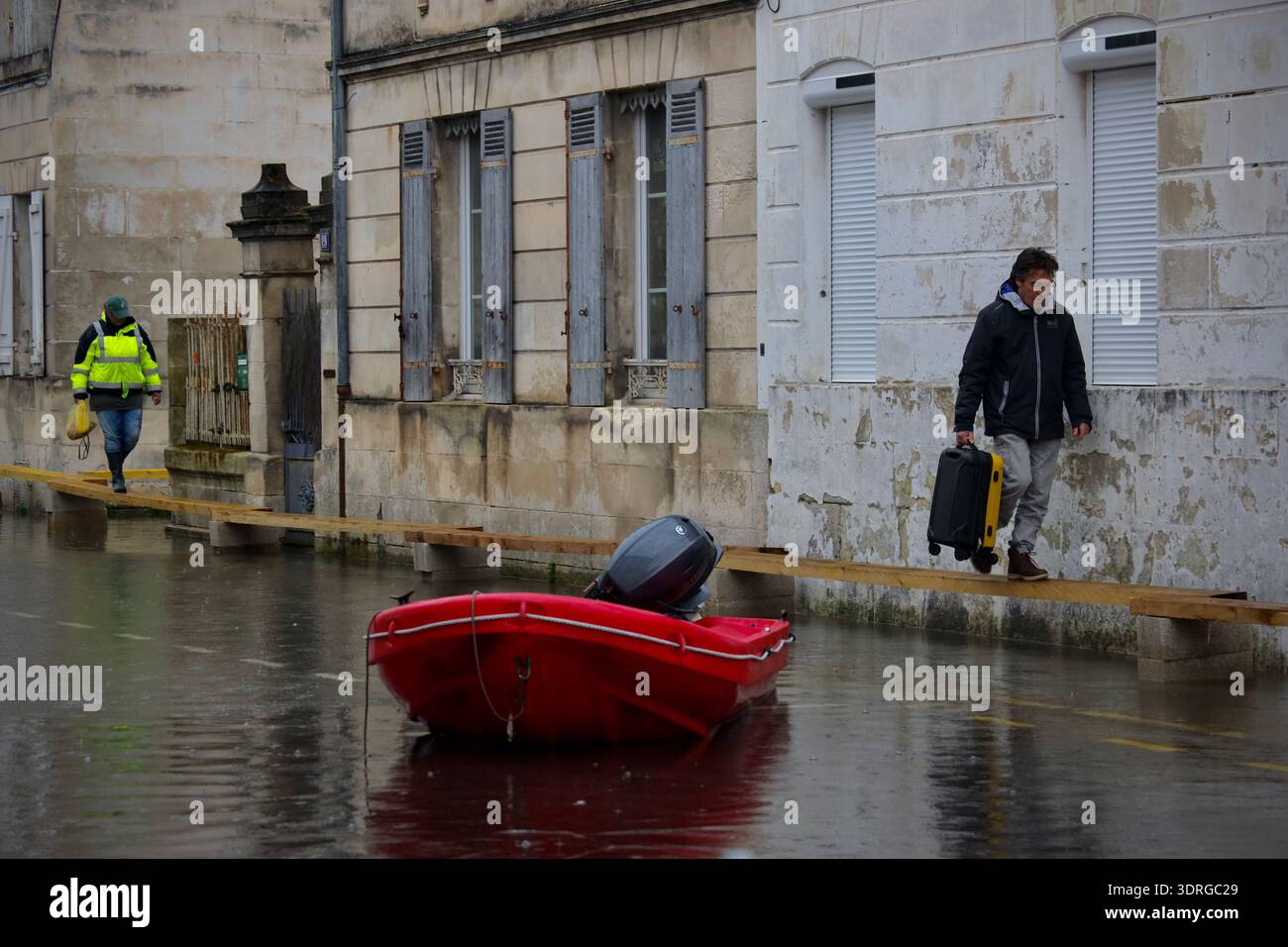 People walk along raised floorboards in a flooded street of Saintes as ...