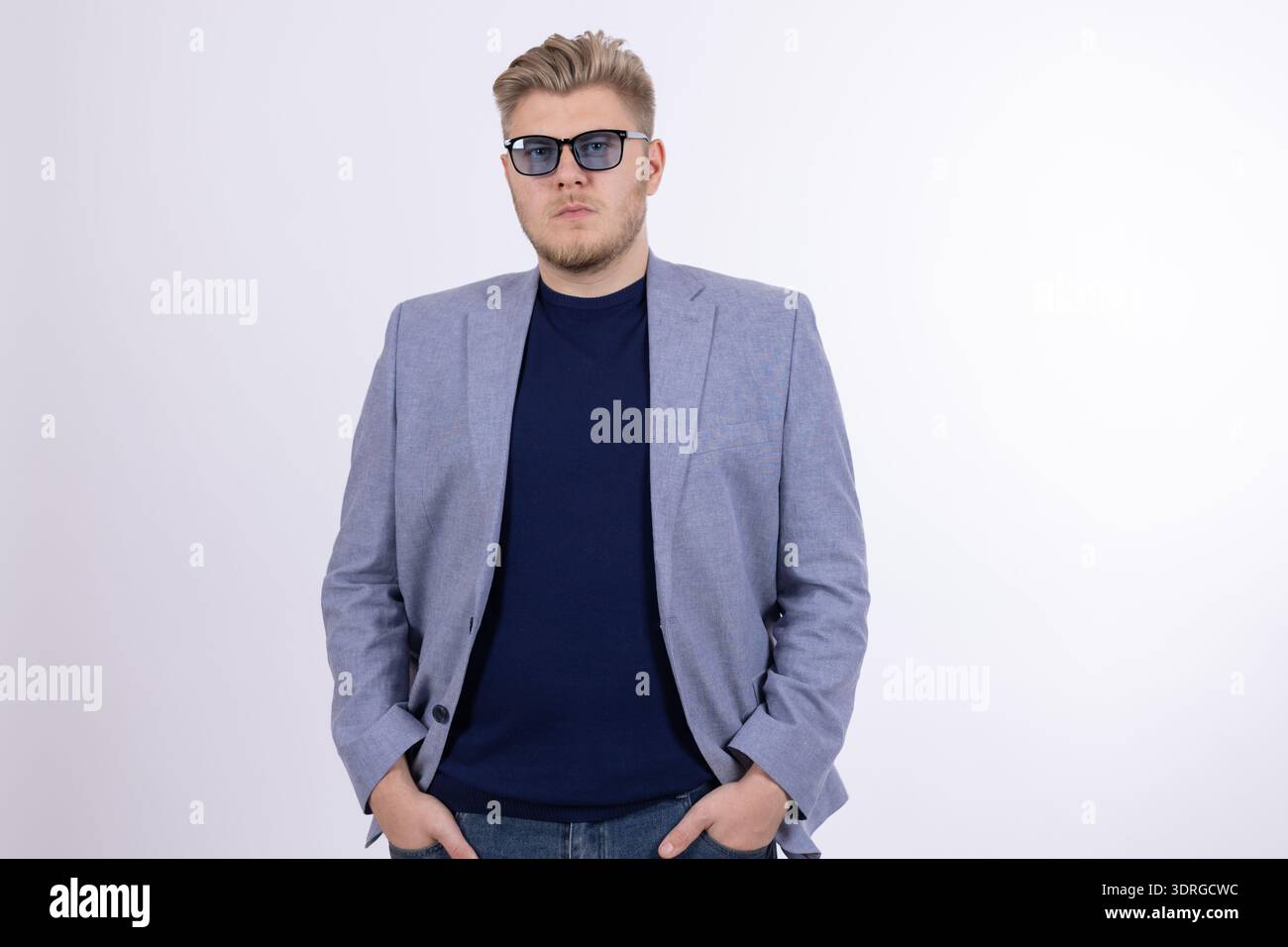 Confident man in blue jacket posing with hands in pockets Stock Photo