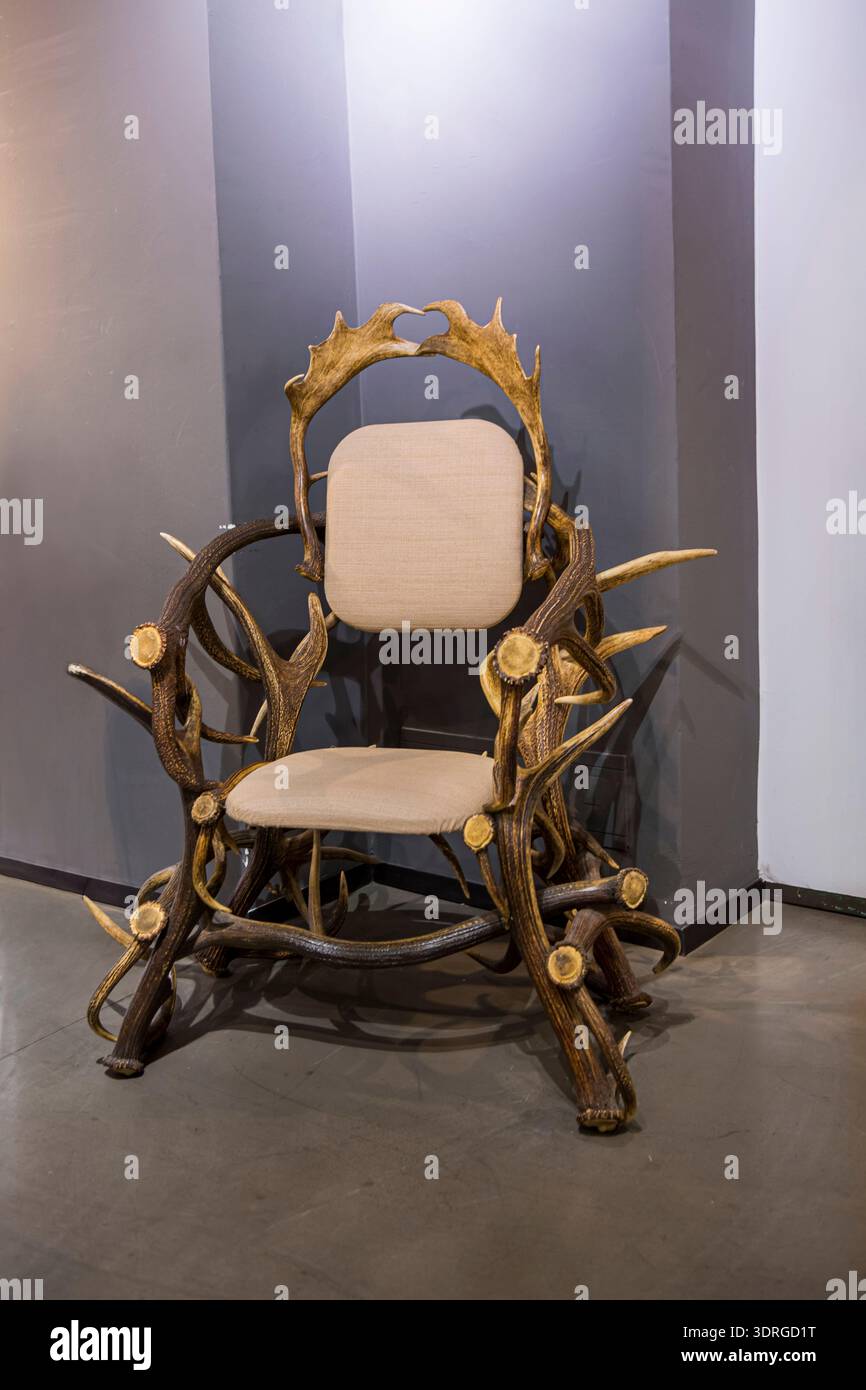 Rustic Throne A rustic antler chair throne with beige cushions displayed against a ...