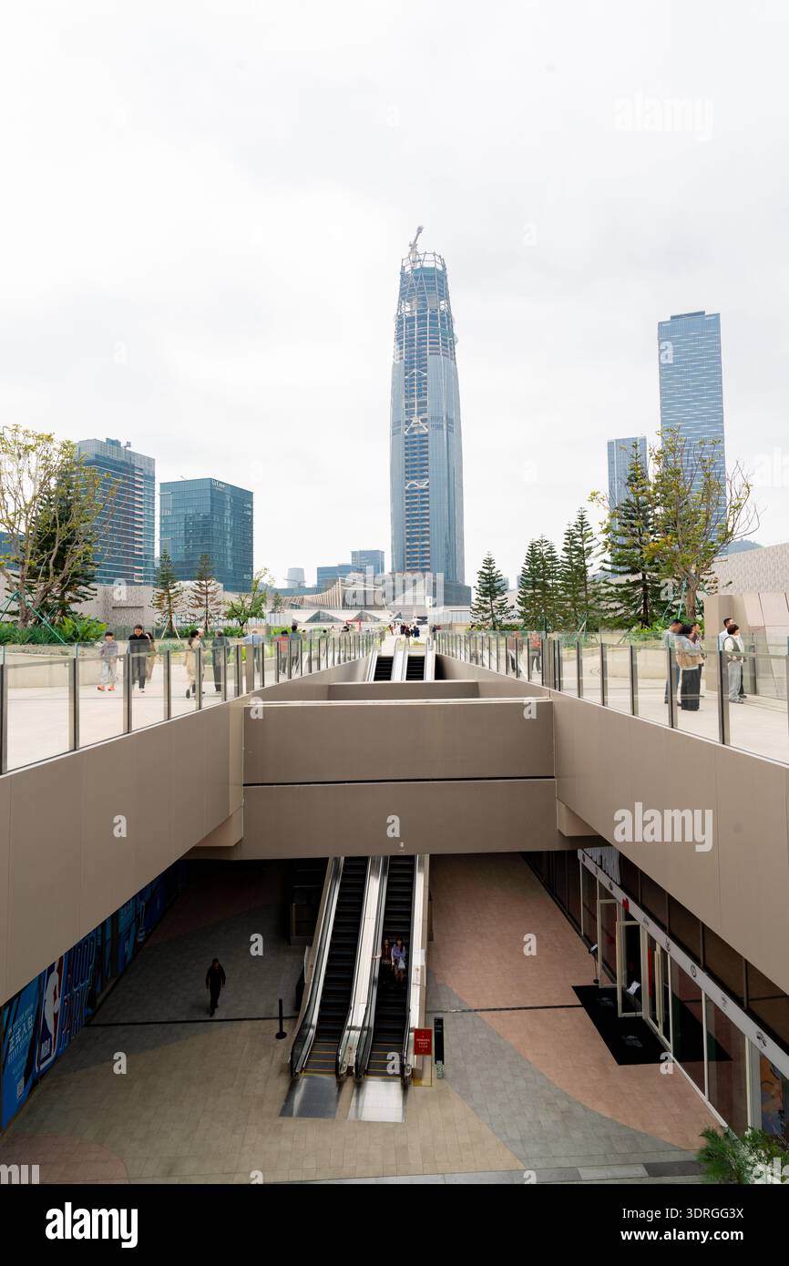 Modern urban plaza with escalators leading to elevated walkway ...