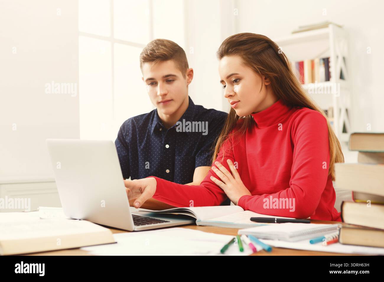 Students Study Together in a Cozy Space While Using a Laptop and Taking Notes on a Project Stock Photo