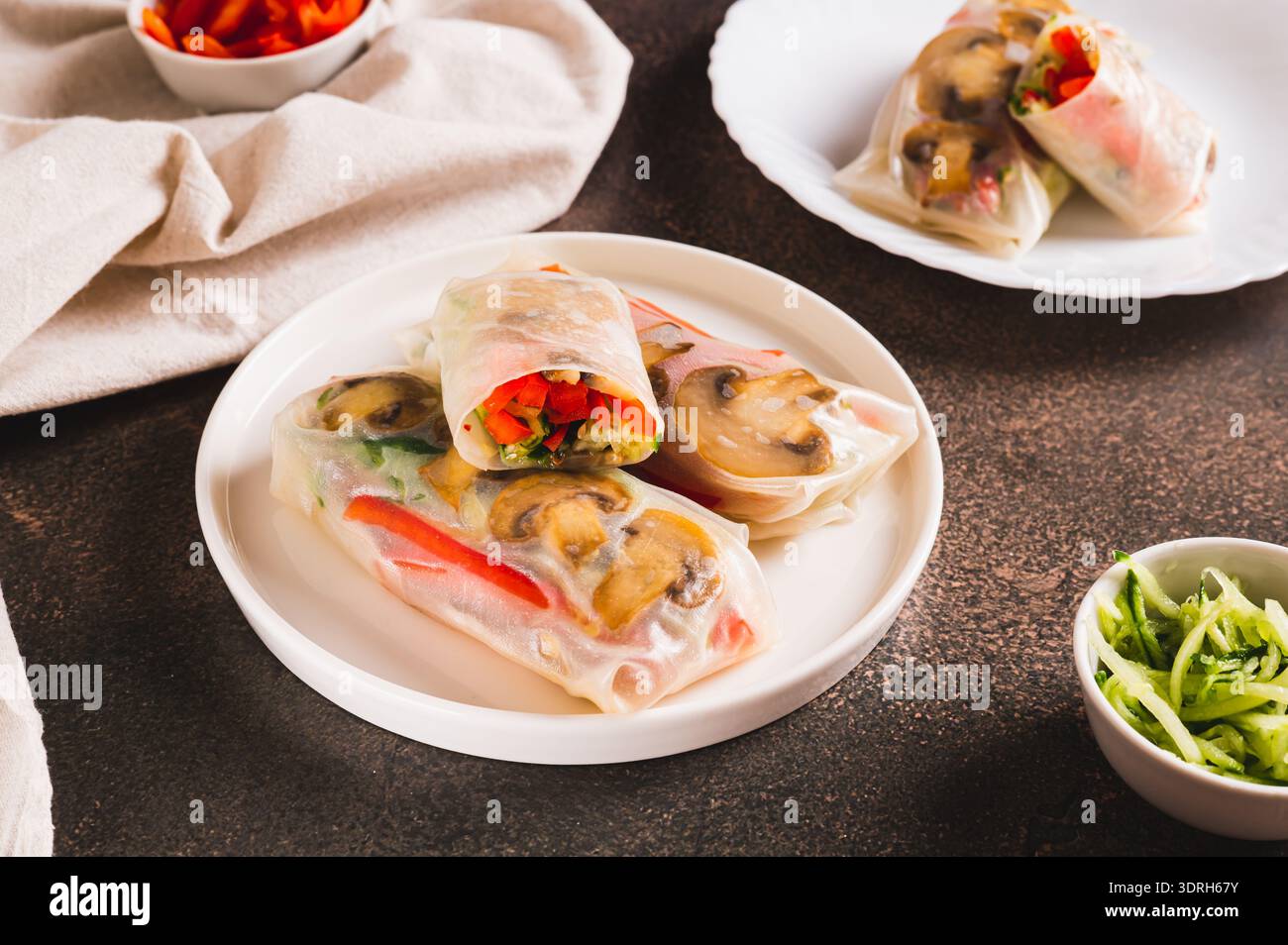 Delicious spring rolls with vegetables and mushrooms in rice paper on a plate on the table Stock Photo