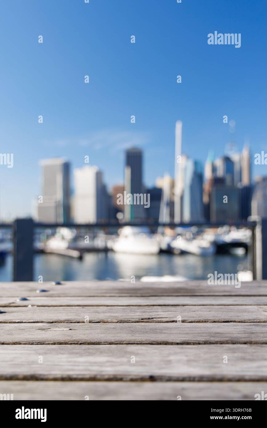 An empty wooden barbecue table set outdoors with a blurred view of the iconic Manhattan skyline Stock Photo