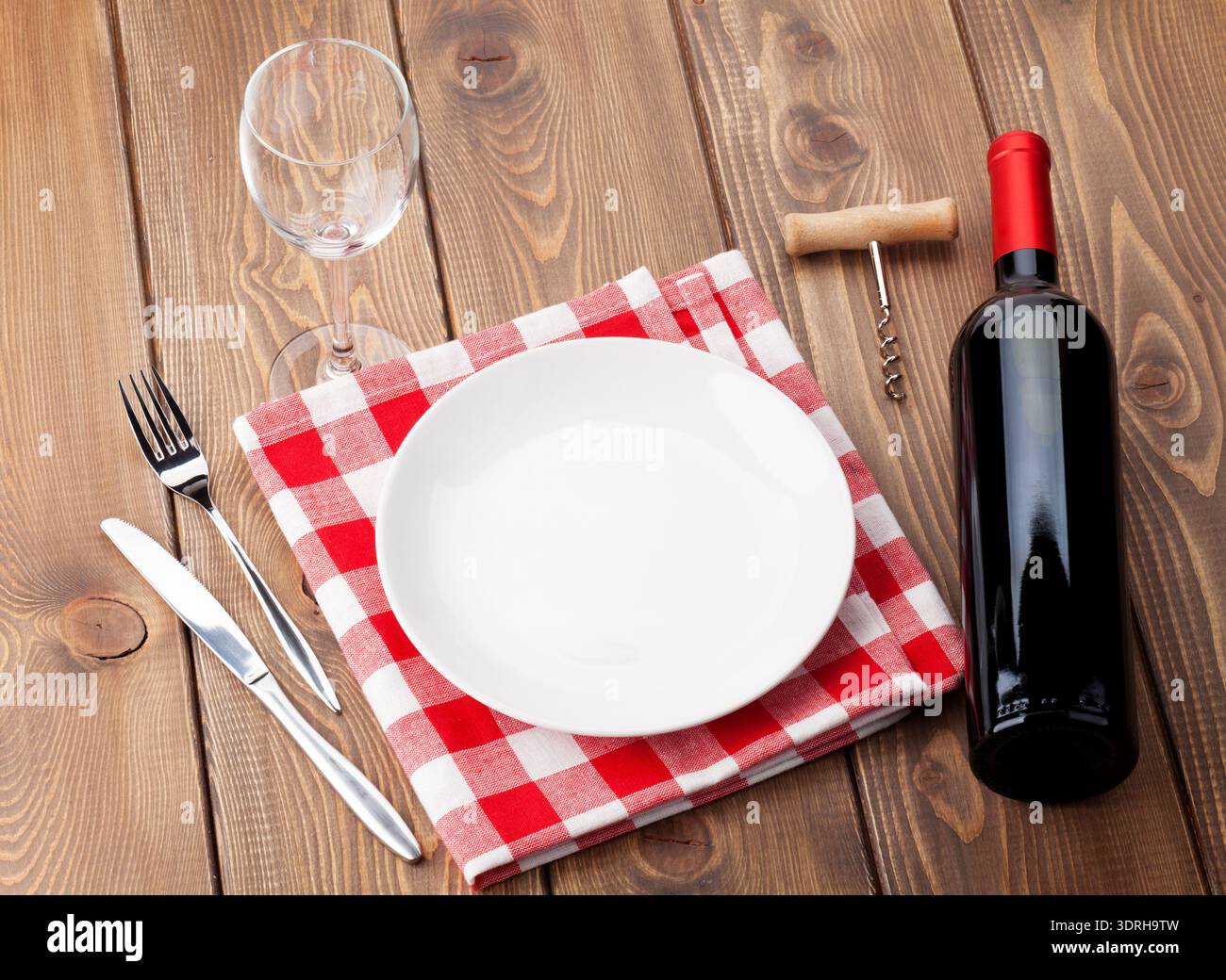 Table setting with empty plate, wine glass and red wine bottle Stock Photo