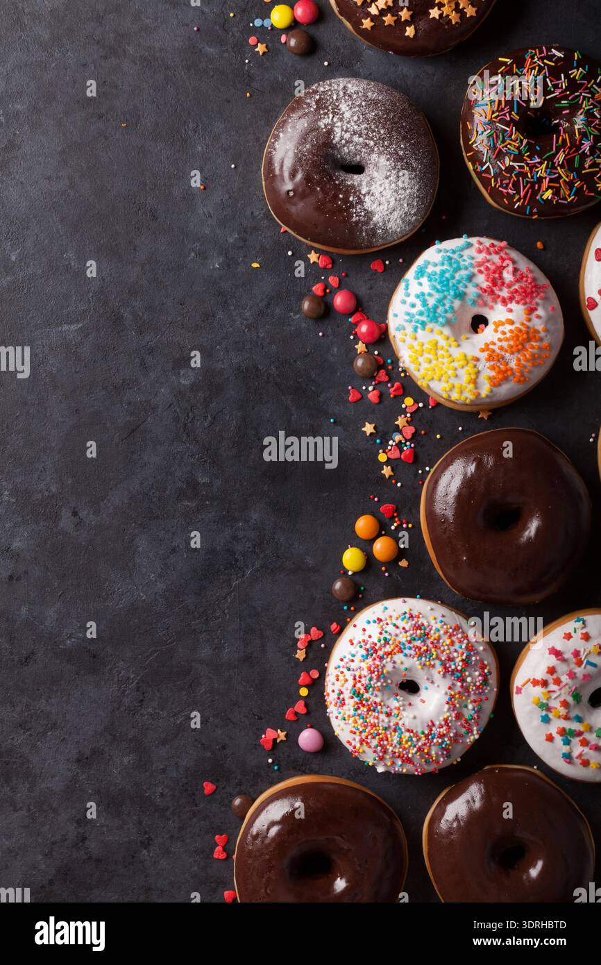 Colorful donuts on stone table. Top view with copy space Stock Photo