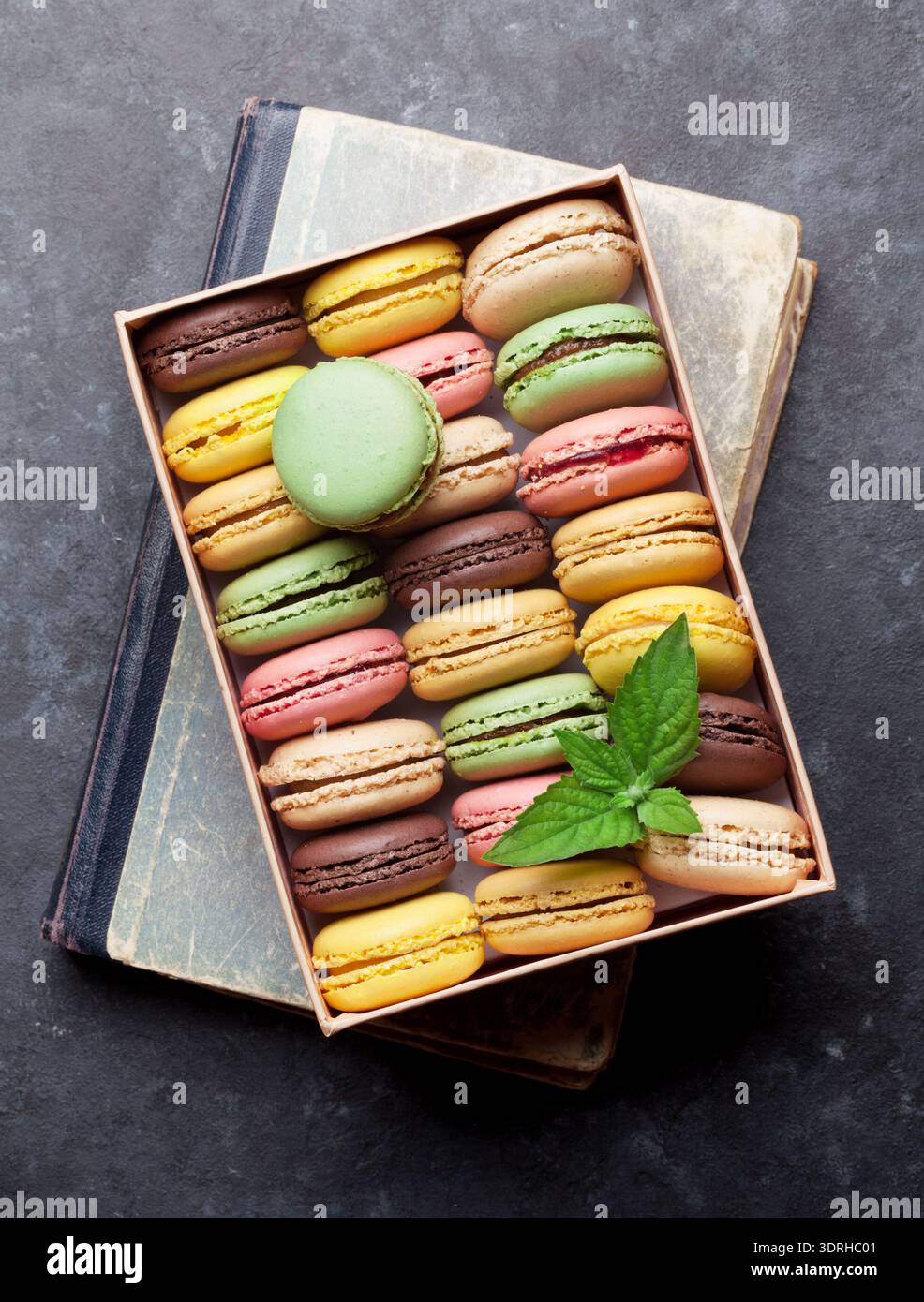 Colorful macaroons in a gift box on stone table. Sweet macarons. Top view Stock Photo