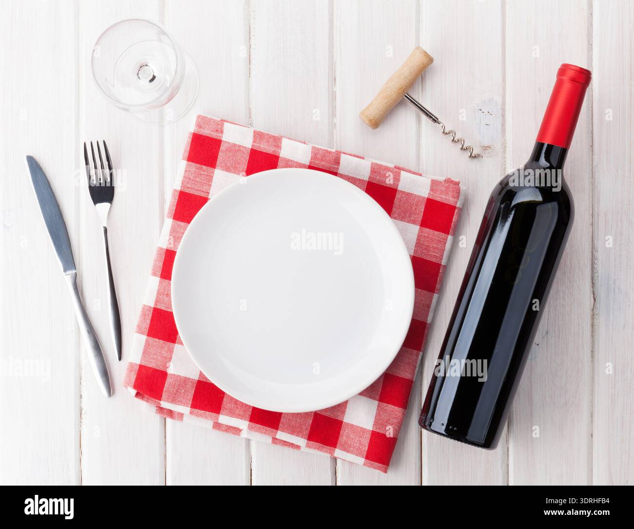 Table setting with empty plate, wine glass and red wine bottle Stock Photo