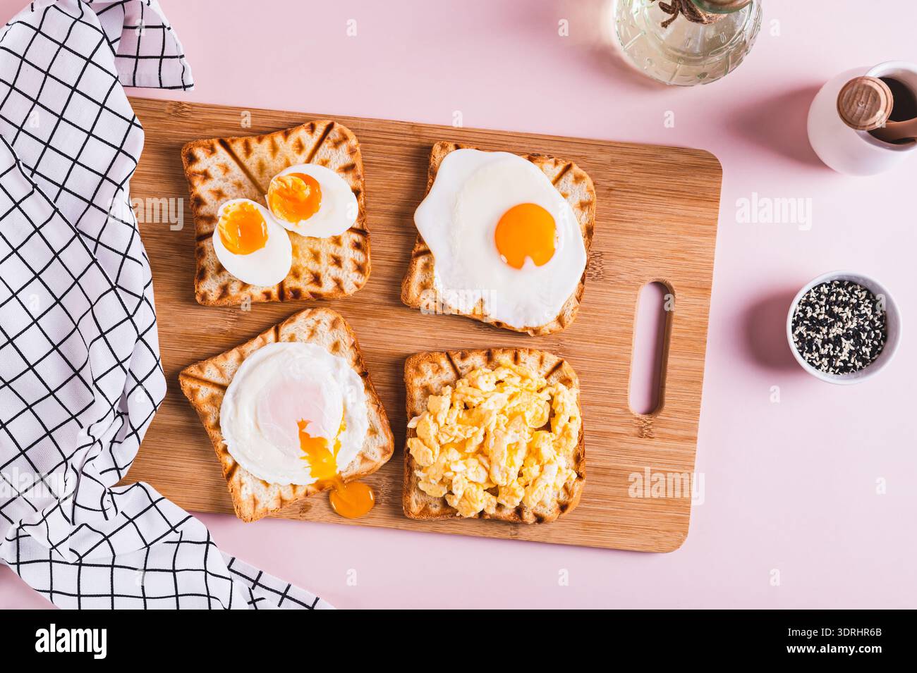Scrambled egg, poached egg, fried egg, boiled egg on toast on a board top view Stock Photo