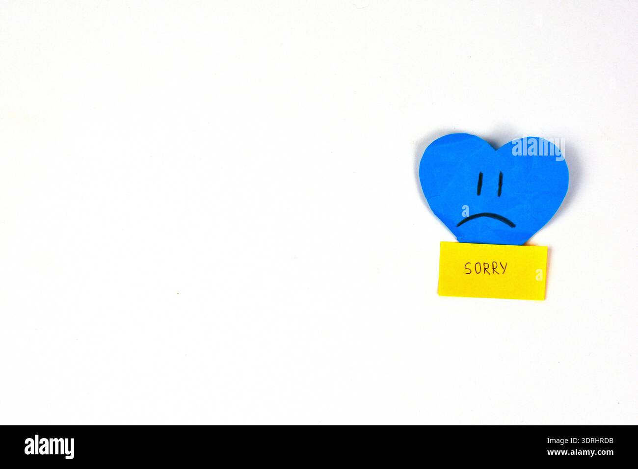 Blue heart with sad facial expression and yellow sticky note saying ...