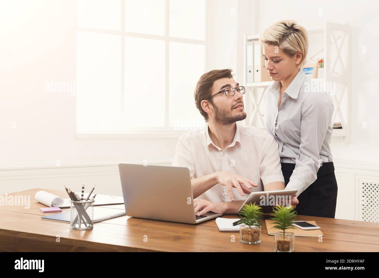 Office Collaboration Between Two Colleagues During a Workday in a Modern Workspace Stock Photo