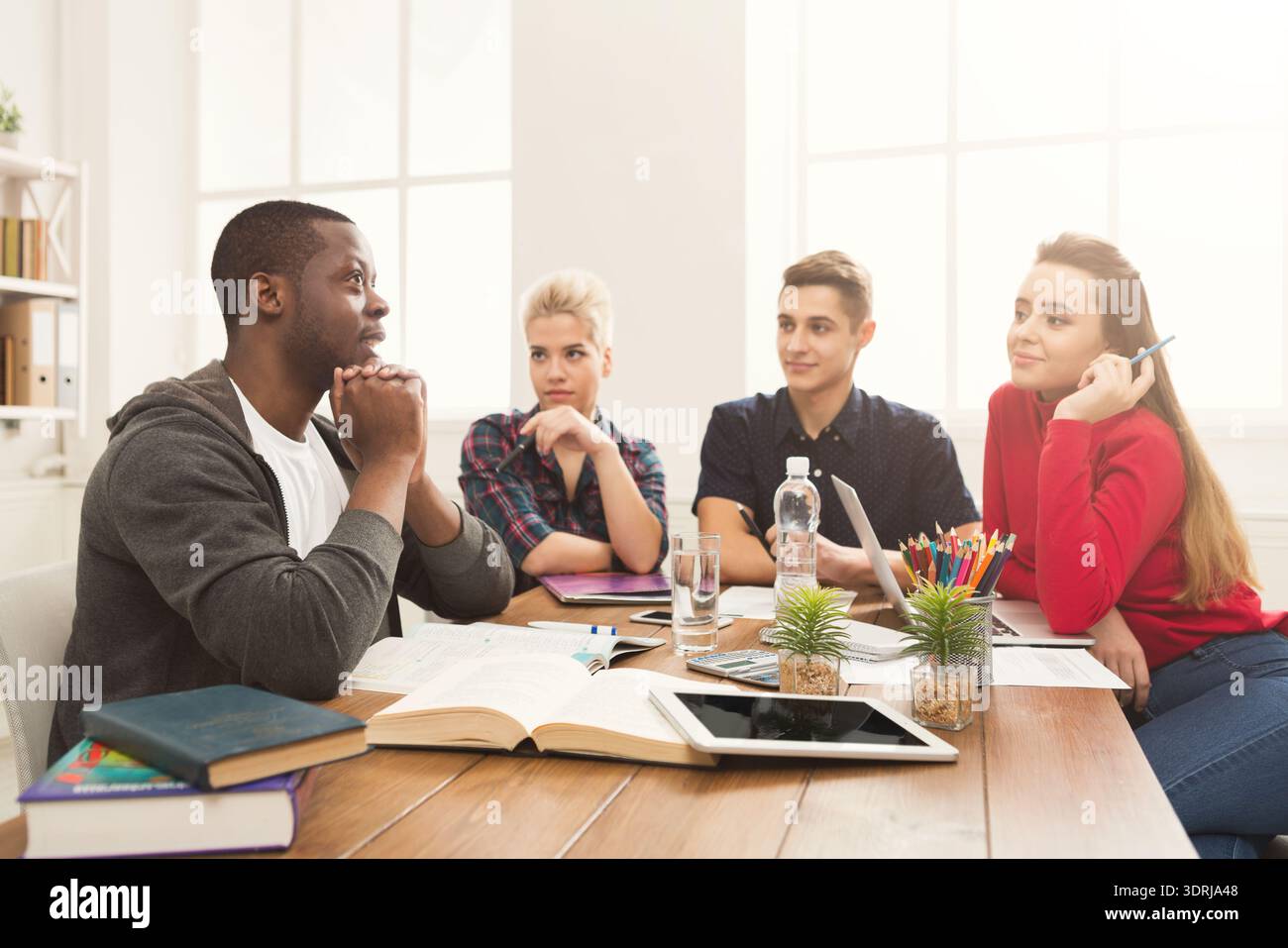 Students Collaborate on a Project During Study Session in Bright Room Stock Photo