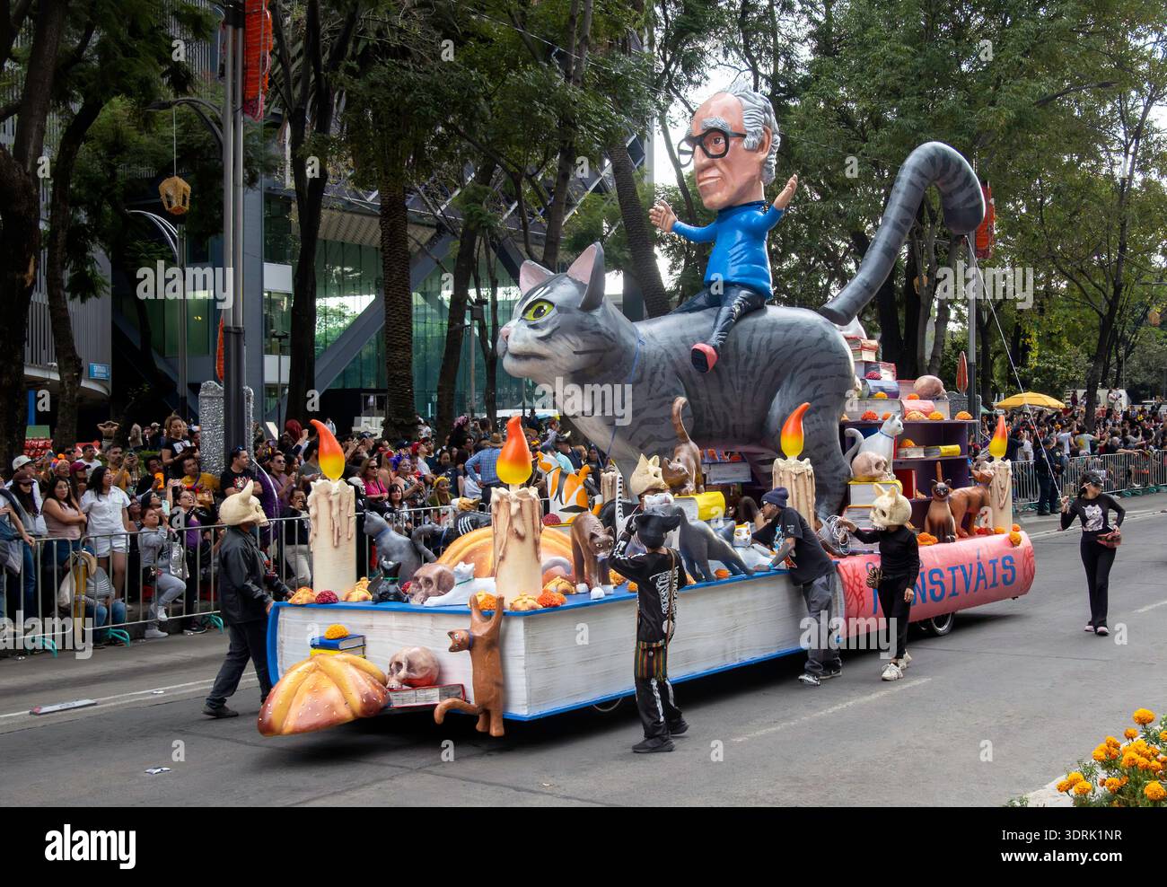 A parade float on the Day of the Dead in Mexico City, Mexico with a  giant statue of Carlos Monsivais, cats, candles and books Stock Photo