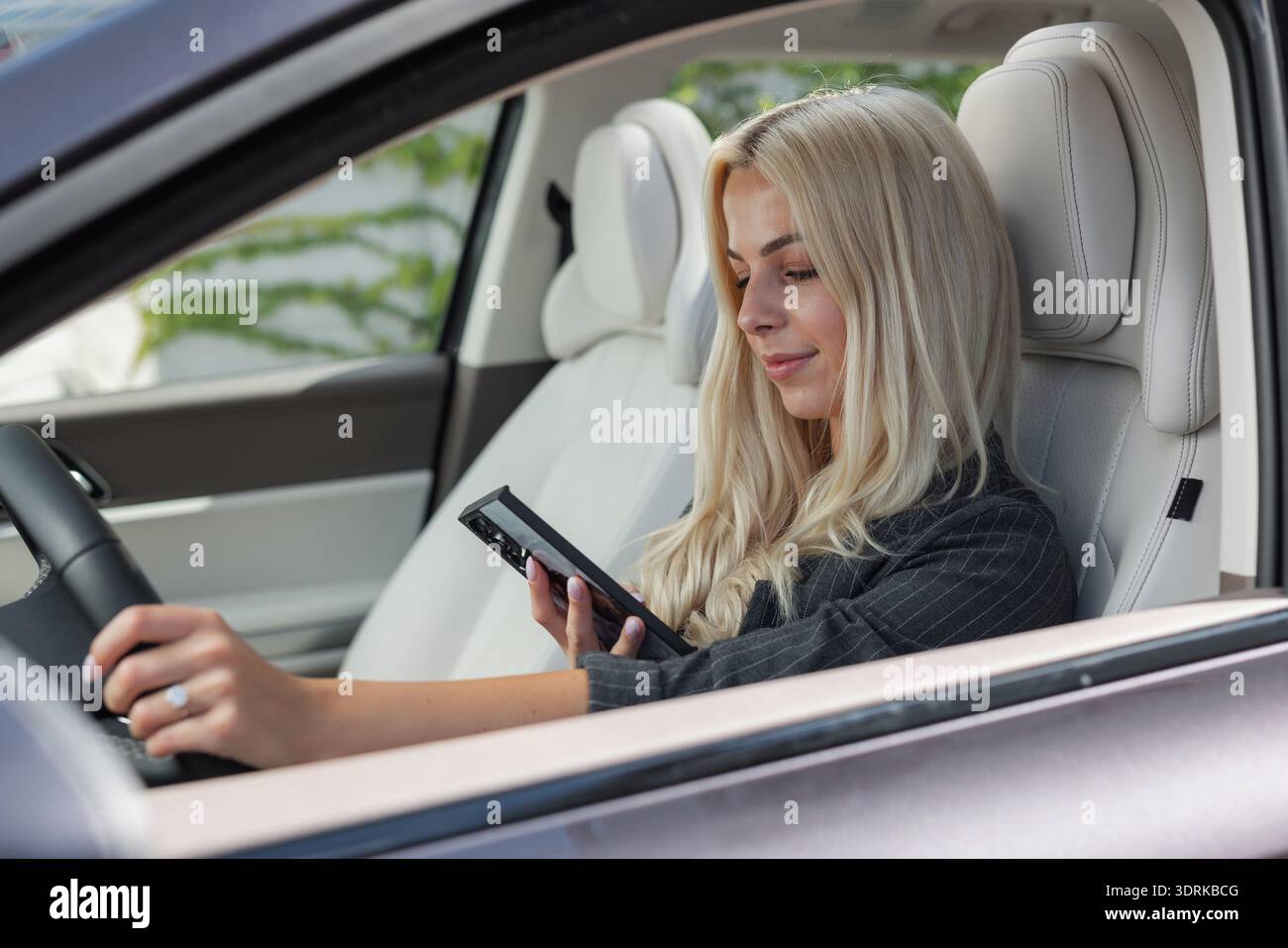Woman reckless driving a car while looking at a smartphone and texting. Stock Photo