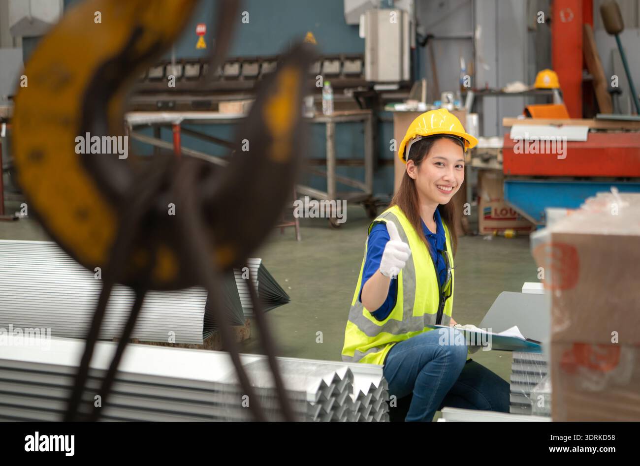 Young female workers are talking and inspecting steel plates for multipurpose forming Stock Photo