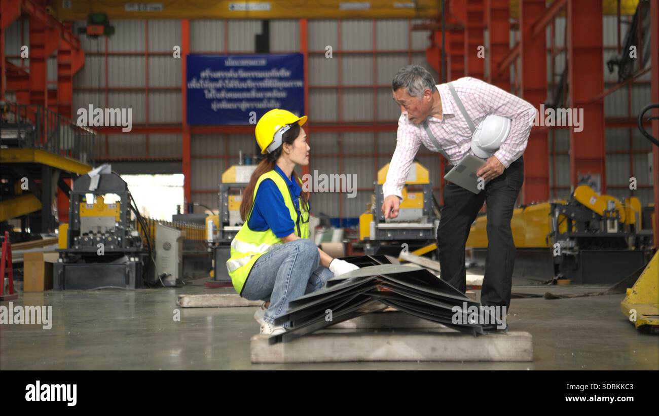 Senior engineers and young female workers are talking and inspecting steel plates Stock Photo