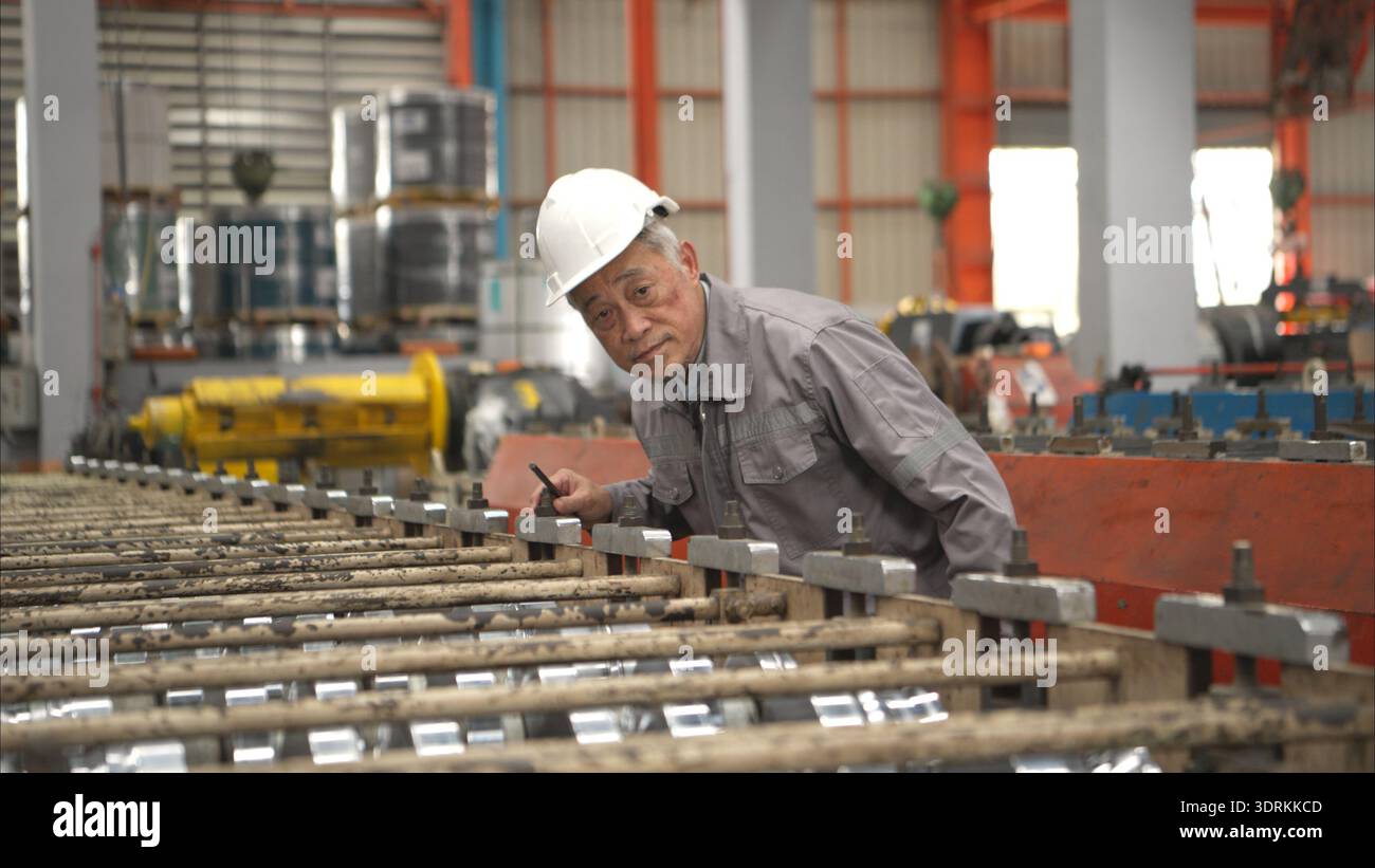 Senior experienced technician checking large machine on a production line Stock Photo