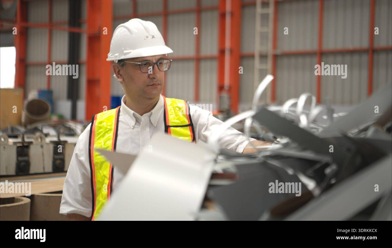 Industrial worker inspecting inside a large metal tube in a factory wearing safety helmet Stock Photo