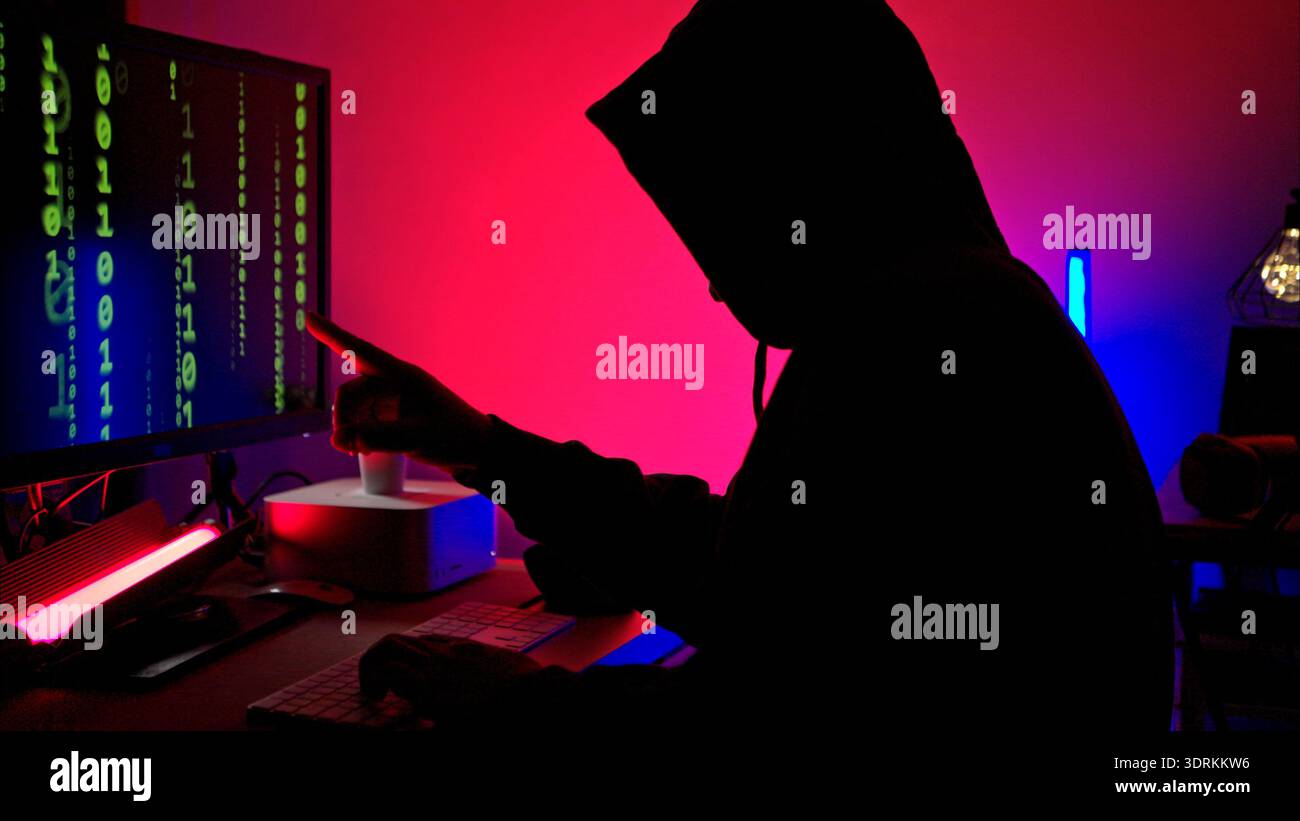 An expert hacker is decrypting data while hiding their face Stock Photo
