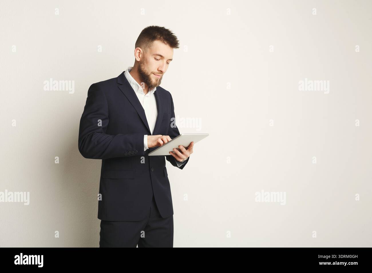 Businessman Using Tablet in a Modern Office Setting During a Workday Stock Photo