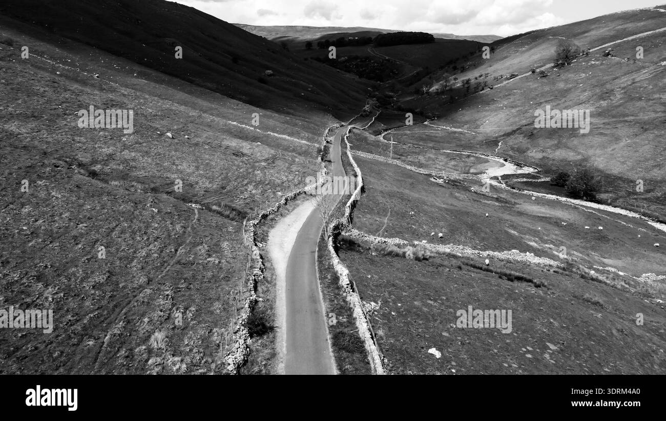 Aerial view of a winding road and stream through a black and white ...