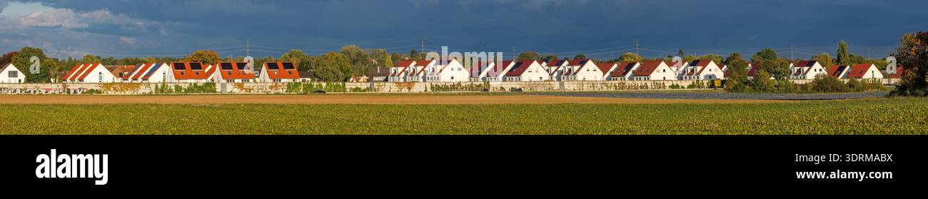 Panoramic photo of the buildings of a single-family terraced housing estate with a noise barrier and a field in the foreground i Stock Photo