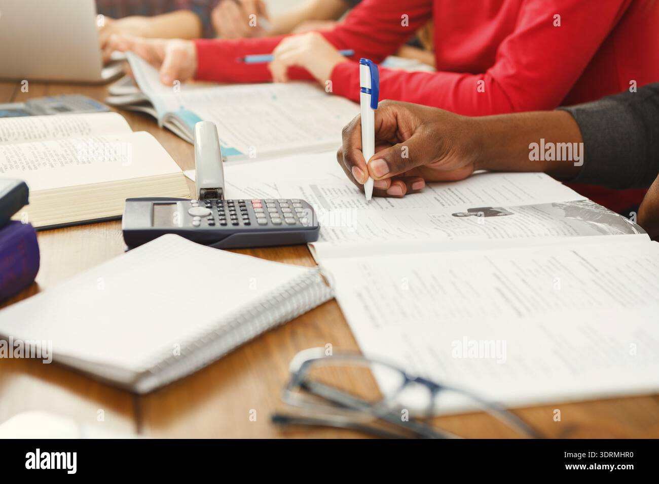 Students Engaged in Collaborative Study Session With Books and Notes on a Table Stock Photo